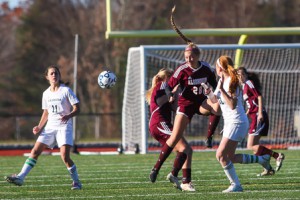 Algonquin junior Meagan Stassi (#28) heads the ball away from Nashoba’s Kylie Lance (#12).