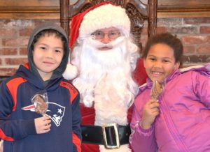 The Erickson siblings – Joshua, 9, and Jadeira, 7 – get a chocolate pop from Santa Claus at Colonial Candies in Bolton. Photo/Ed Karvoski Jr.