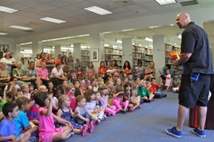 An enthusiastic crowd of children listen as magician Greg McAdams plays tricks on them. 