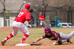 Algonquin’s Alex Pappas safely dives back to first base as St. John’s Trevor Gustavson receives the pickoff throw.