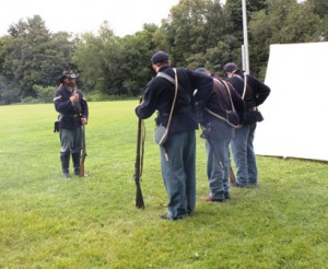 Corporal Russell Marchand and other reenactors reload their weapons.