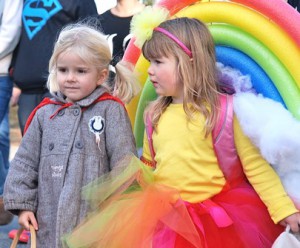 Three-year-old friends walking together are Claire McDougall as Little Red Riding Hood and Scarlett Spencer as a rainbow. 