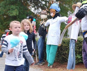While enjoying cotton candy, Jake O’Connell, 5, and his sister Sadie, 7, view entries in the scarecrow contest in front of the Community House.