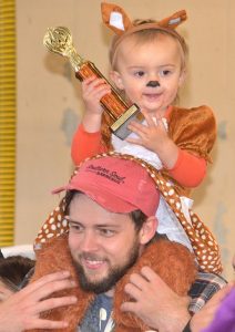 Vayda Taylor, 1, displays the trophy that her baby doe costume won for cutest in her age category with help from her proud father, Zachary.