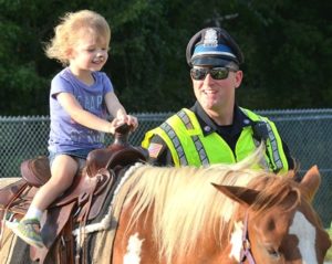 After getting her face painted, 5-year-old Claire rides a pony guided by her father, Detective Sean McCarthy.