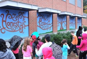 Despite a rainy afternoon Oct. 28, Quinn Middle School students check out the new outdoor mural following an unveiling ceremony inside. (Photo/Ed Karvoski Jr.)