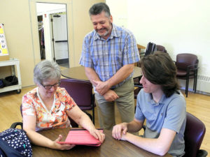 Patrick Crowley Poirier, a student at the Assabet Valley Regional Technical Vocational High School, assisted Margaret Theodoss with her iPad recently at the Hudson Senior Center. Looking on is Steven Pleau, a teacher in the Assabet Computer Programming and Development program, who brings students to assist at the senior center monthly. 