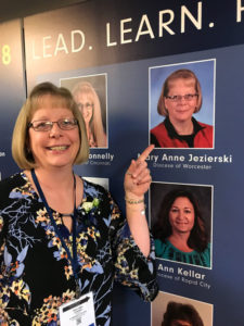 Mary Anne Jezierski stands by her photo on the board announcing the winners of the 2018 NCEA Lead, Learn, Proclaim award in Cincinnati, Ohio. Photo/submitted