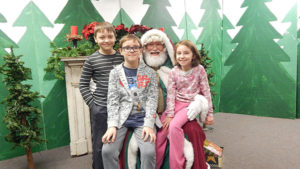 Madeline, 7, Ethan, 9 and Benjamin, 10, pose for a photo with Santa Claus at St. Mary’s Annual Holly Fair Dec. 2. Photo/Melanie Petrucci 