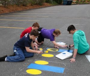 Volunteers paint number graphics on the pavement.