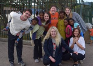 Peyton Heller (far right, front, in white t-shirt) and other students from Lead Abroad pose with Heller's host family at a nearby township where the group completed a week of community service. (Photo/submitted)
