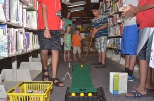A young man lines up the putt in the library stacks.
