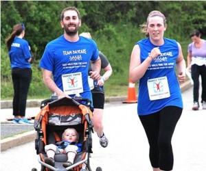 Eric and Emily Luth with their son, Ben, 16 months, stroll toward the finish line. Emily is a teacher at NECC.