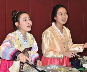 Eighth-graders Sherry Lin and Sue Lee serve South Korean scallion pie.