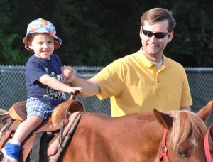 Austin Bishop, 2, is guided by his father, Chris, while riding a pony.