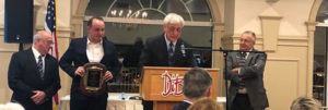 Det Klein speaks at the podium during the Hall of Fame awards banquet. Also on stage are (l to r) Ed Gangi, ICBA vice president; Jonathan Beadreau, who nominated Klein; and Ralph Semb, ICBA Hall of Fame chair and awards banquet master of ceremonies. 