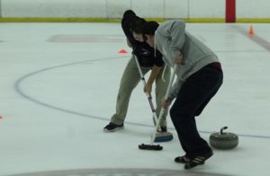 Two curlers at the Aug. 7 open house sweep ahead of a stone. The first half of the open house was devoted to throwing stones. The second half taught attendees how to sweep to make stones go farther. Photo/Dakota Antelman 