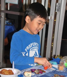 Caleb Zhou, 7, plays with a dreidel while learning about Hanukkah customs. 