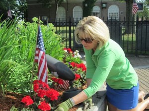 Alyce Luippold of the Westborough Garden Club takes time on a sunny day to care for the Civil War monument garden where she planted geraniums and petunias. (photo/Zenya Molnar)