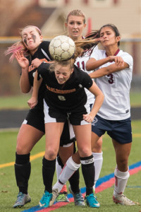 Marlborough’s Abby Chrisafedeis (#8) head the ball out of a crowd of players,
