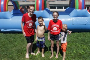 After sliding through the waterslide with junior staff members Miles Henderson and Gabriella Daniele, campers Hollis Keegan (left) and Tyler Cutone give a big thumbs-up.