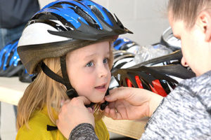 Elizabeth Dumas, 4, is fitted for a bike helmet by Kelly Tyler, Boroughs Y health and wellness director. Photo/Ed Karvoski Jr.