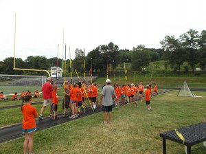 Coach Doug Lang (gray shirt) and Coach Roger Anderson (red shirt) teach campers the basics of pole vaulting.
