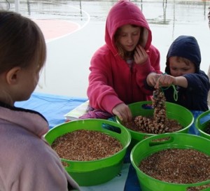 Noa-Lee and Robin Bastien participate in a Girl Scout activity, making birdfeeders from pinecones and seeds, at the Marlborough Earth Day Fair.