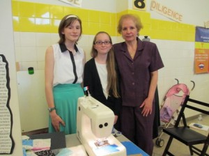 Proud teacher Nora Wagman stands next to French students Rose Shade and Megan Dion, who chose to use sewing as a means to communicate the their interest in Parisian fashion.