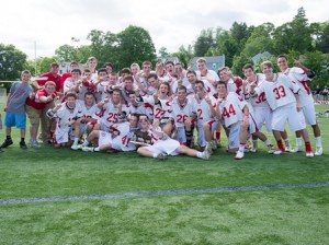 Members of the St. John's High School boys lacrosse team pose with their Massachusetts Boys Lacrosse Central Division 2 trophy held by co-captains Aidan Fox (#21, right) and Hunter Burdick (#41, left).